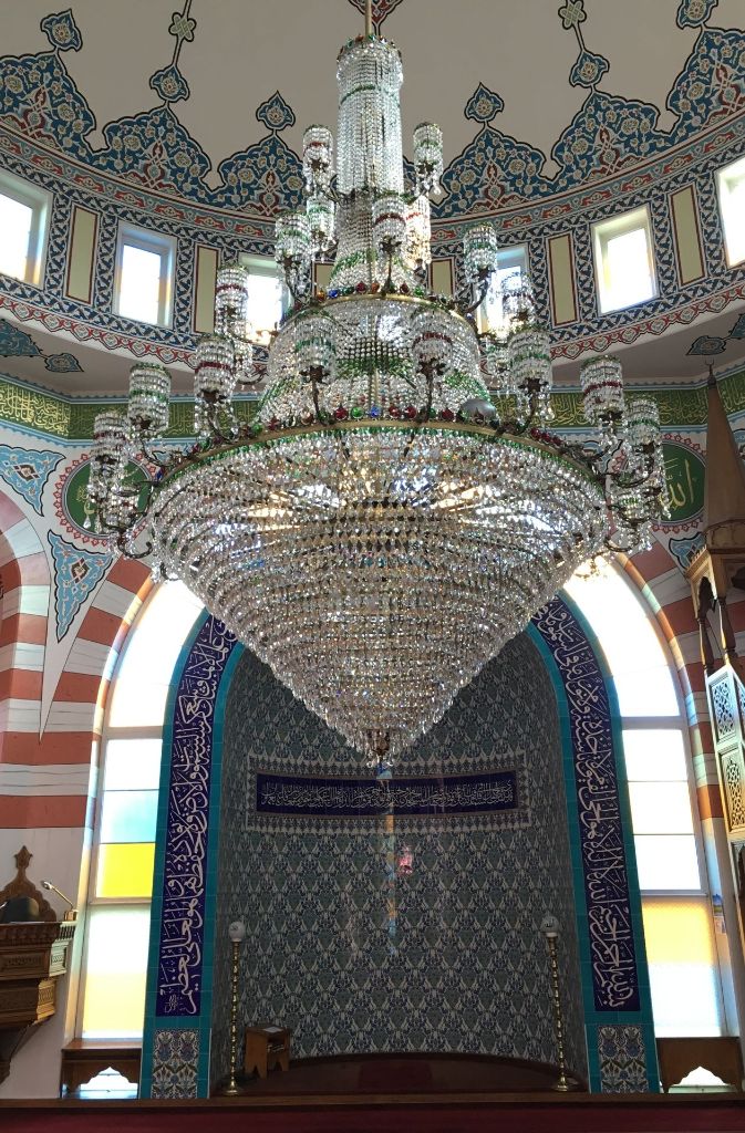 Der Kronleuchter unter der Kuppel der Moschee wiegt etwa 1,6 Tonnen, erzählen die Männer des Moschee-Vereins. In der blauen Gebetsnische betet der Imam, der Vorbeter.