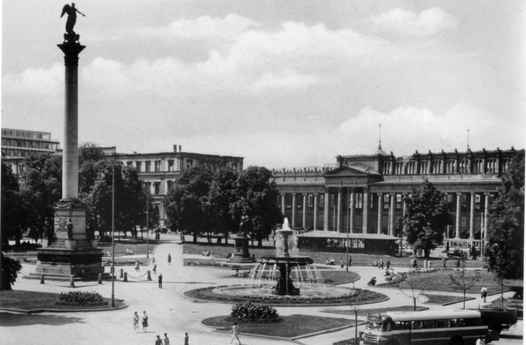 Dieses Bild zeigt den Schlossplatz in den 1950er Jahren. Im Hintergrund ist noch die Ruine des Kronprinzenpalais zu sehen, die später unter Protest der Bürger abgerissen wurde. Auch der Königsbau ist noch beschädigt. Wo heute der Pavillon auf dem Schlossplatz steht, war damals noch ein Wartehäuschen für die Straßenbahn-Fahrgäste.