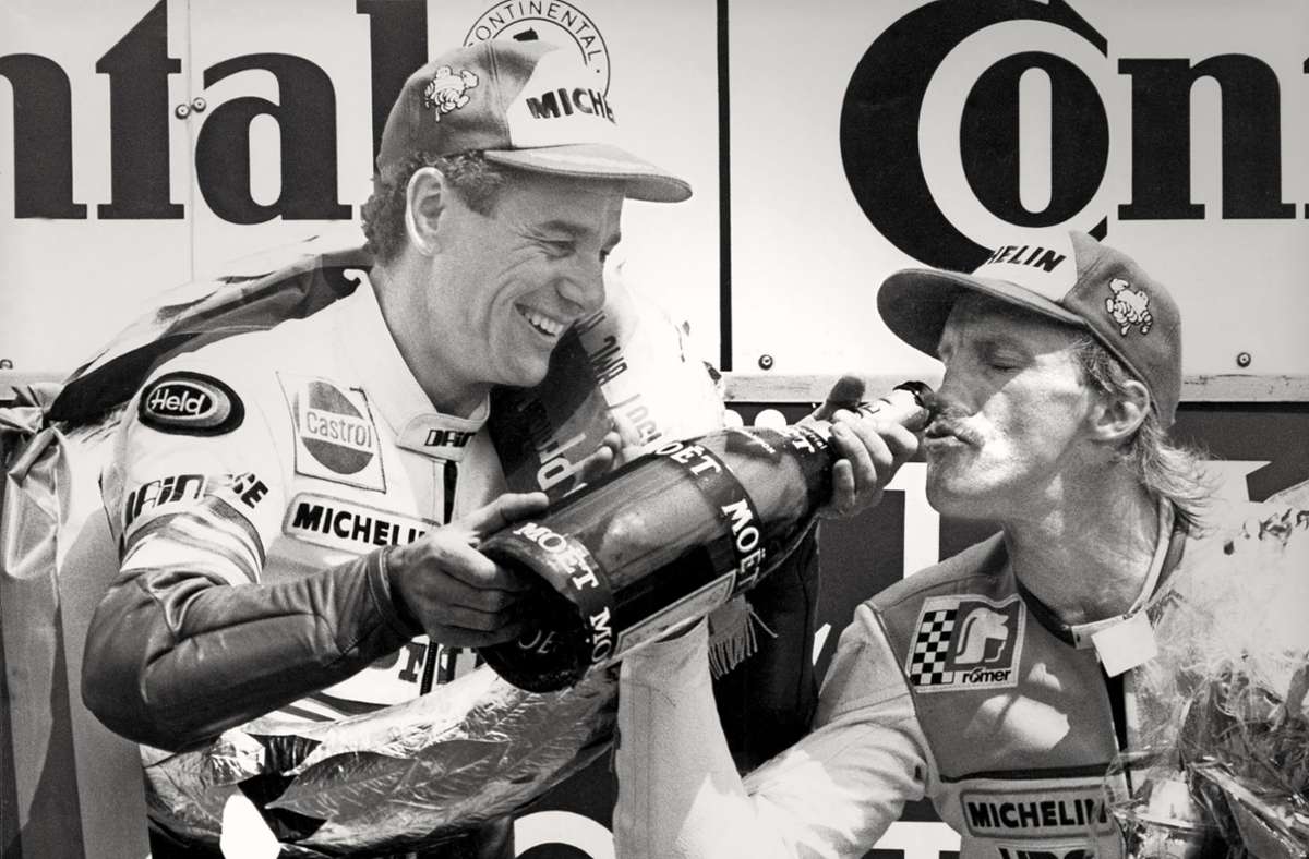 Honda-Kollege Toni Mang (links) gönnt Reinhold Roth 1987 bei der Siegerehrung in Hockenheim  einen Schluck Champagner aus seiner Magnumflasche. Foto: imago/Norbert Schmidt