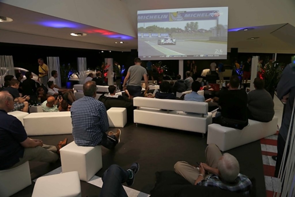 Motorsport-Fans schauen sich das Rennen im Porsche-Museum an.