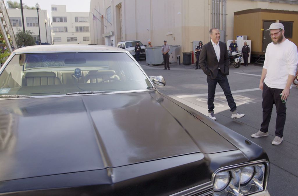 Jerry Seinfeld mit Seth Rogen vor einem 1976er Dodge Royal Monaco, einem ehemaligen Streifenwagen: „das „Blues Brothers“-Auto, wie Rogen begeistert anmerkt.
