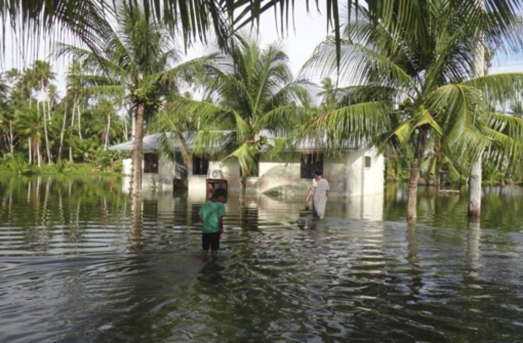 Sie trifft der Klimawandel ganz besonders: Teile der Marshall-Inseln wurden in diesem Jahr schon zwei Mal überschwemmt: hier eine Mutter und ihr Kind vor deren gefluteten Haus auf Kili. Foto: AP