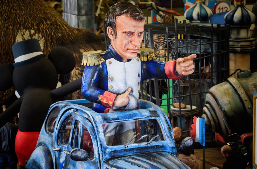 Der französische Staatspräsident Emmanuel Macron steht in Napoleon-Pose auf einem Motivwagen unter dem Motto „En Marche!“.