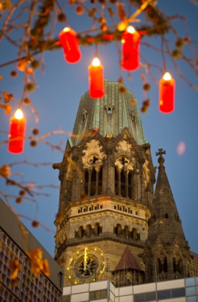 Eine Kerzen-Lichterkette hängt in Berlin an einem Baum auf dem Weihnachtsmarkt an der Gedächtniskirche.