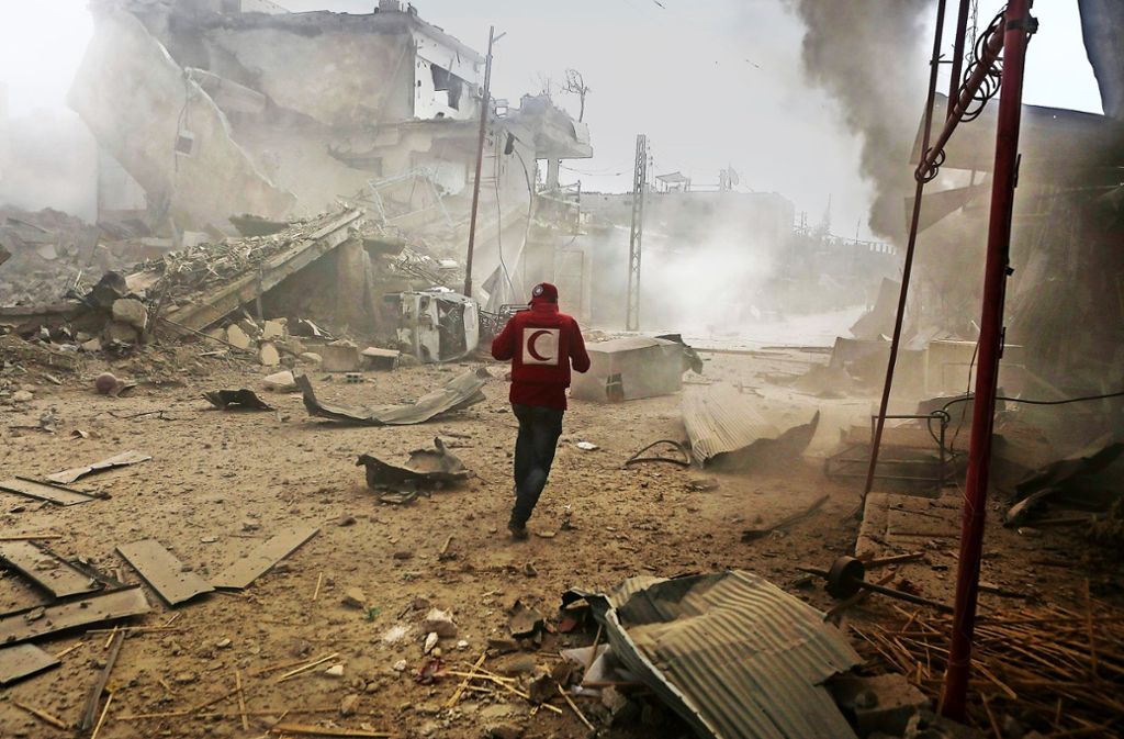 Ein Mitarbeiter des Syrischen Roten Halbmondes eilt durch ein Viertel von Ost-Ghuta nahe Damaskus im Rebellengebiet, das von Angriffen der Luftwaffe getroffen wurde. Foto: dpa