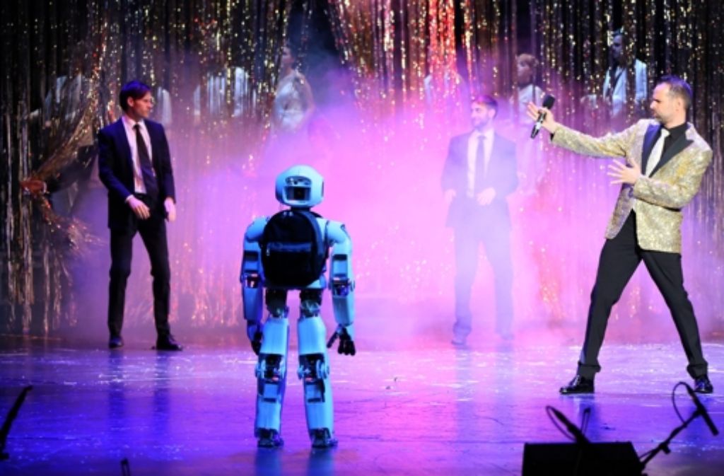 Auch Roboter wollen in Zukunft unterhalten werden, sagt der Professor Manfred Hild – und interpretiert im Glitzerjackett vor seinem Roboter Myon „Feel“ von Robbie Williams.