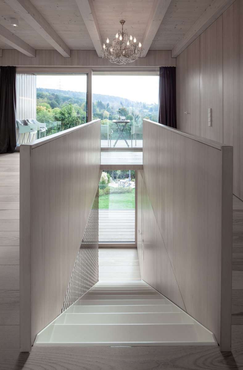 Eine schmale weiße Metalltreppe führt hinter in die Schlaf- und Wohnräume.