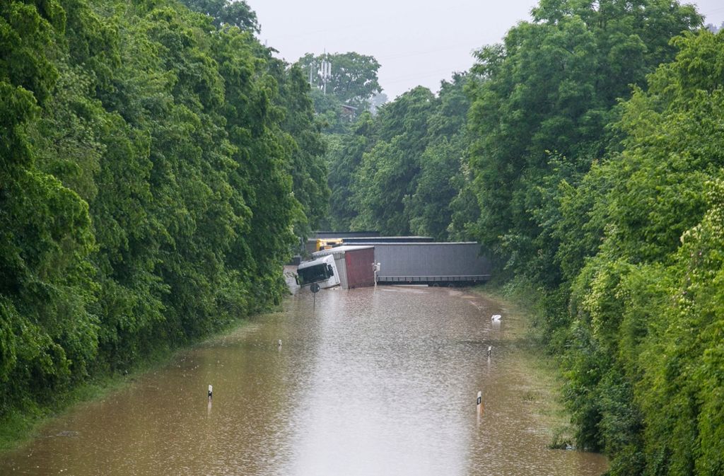 Lastwagen blockieren eine überflutete Landstraße.