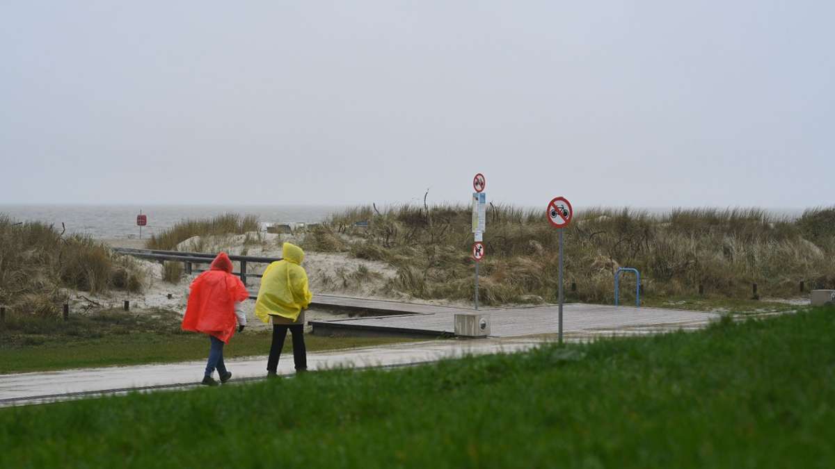 Regenwetter: Zwei Tagesgäste laufen an der Strandpromenade im niedersächsischen Norddeich entlang.