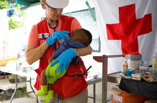 Eine Ärztin des Roten Kreuzes sorgt sich um den verwaisten kleinen Sebastian: Solche Bilder aus Haiti gehen ans Herz. Kinderhändler wittern ihre Chance. Foto: apd