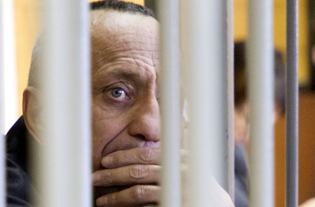 Michail Popkow sieht während der Gerichtsverhandlung durch die Käfigfgtter. Ein Gericht in Irkutsk hat den 53-Jährigen des Mordes an weiteren 56 Frauen schuldig gesprochen und ihn zu einer lebenslangen Haftstrafe verurteilt.