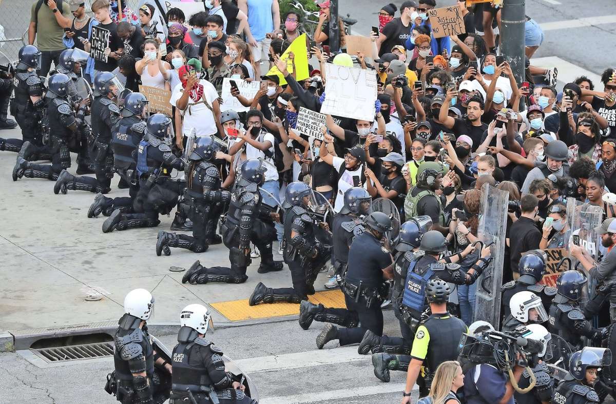 Doch es geht auch anders wie hier in Atlanta/Georgia, wo Polizisten in Solidarität mit den Demonstranten niederknien. Foto: AP/Curtis Compton