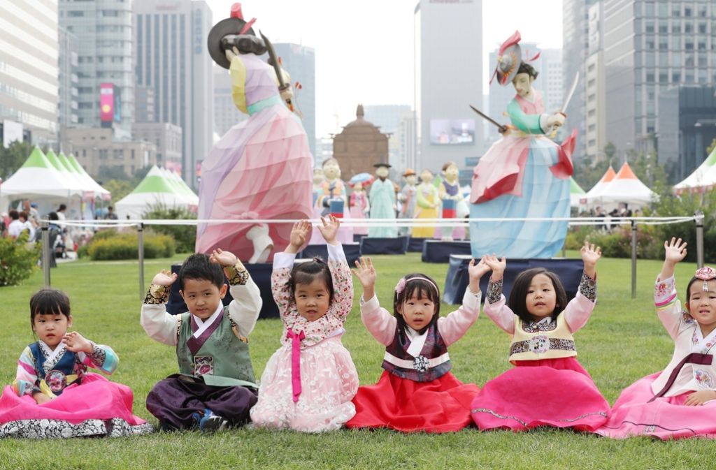 Südkoreanische Kinder sind in die landestypische Tracht „Hanbok“ gekleidet. Sie winken während des Hanbok-Festivals in der Innenstadt von Seoul, Südkorea. Mit 23,58 Millionen Menschen belegt Seoul Platz vier der größten Metropolregionen weltweit.