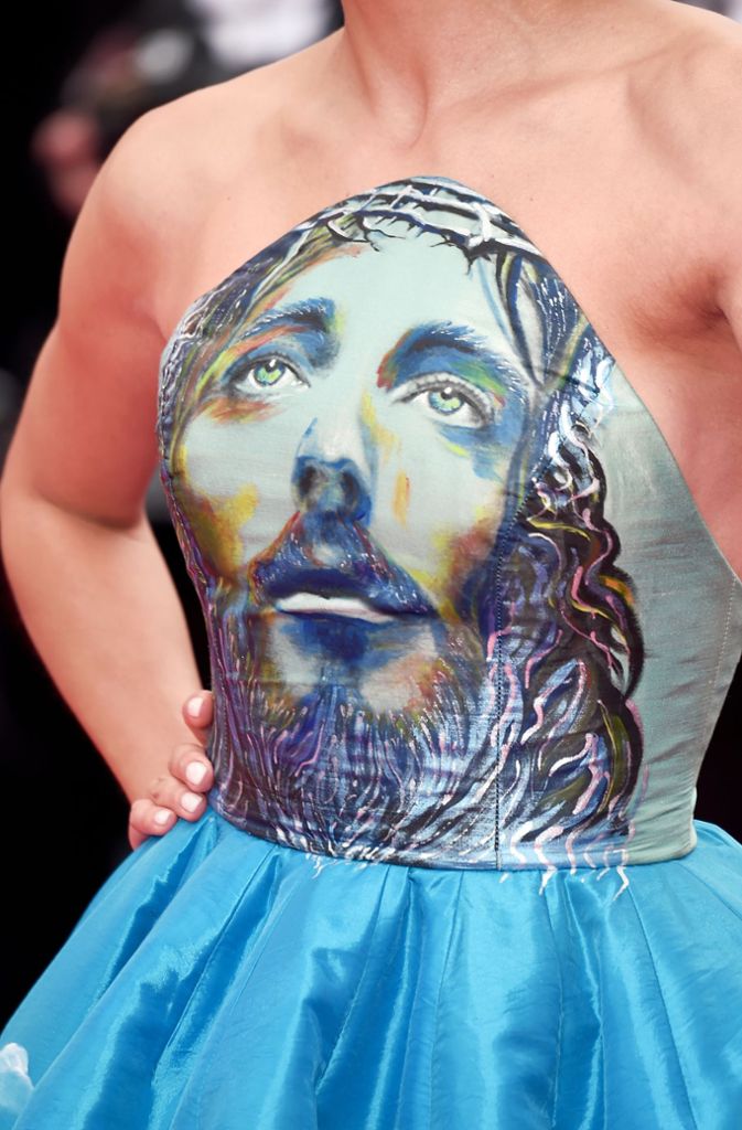 Wer mit Jesus Christus auf der Brust herum spaziert, muss sich nicht wundern, nur Hals-abwärts fotografiert zu werden. Das Kleid, war für die Fotografen offensichtlich ein Hingucker im wahrsten Sinne des Wortes.