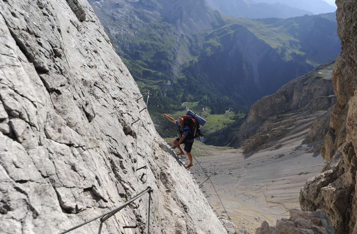 Die letzten Eisensprossen trennen den Barfußwanderer vom Geröllfeld auf der Südseite der Marmolada. Hier erwartet ihn im scharfkantigen Gestein der Dolomiten die schwierigste Etappe der Alpenüberquerung.
