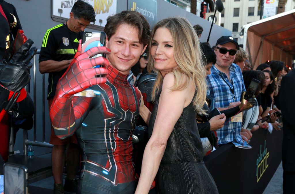 Schauspielerin Michelle Pfeiffer posiert mit einem als Spiderman verkleideten Fan.