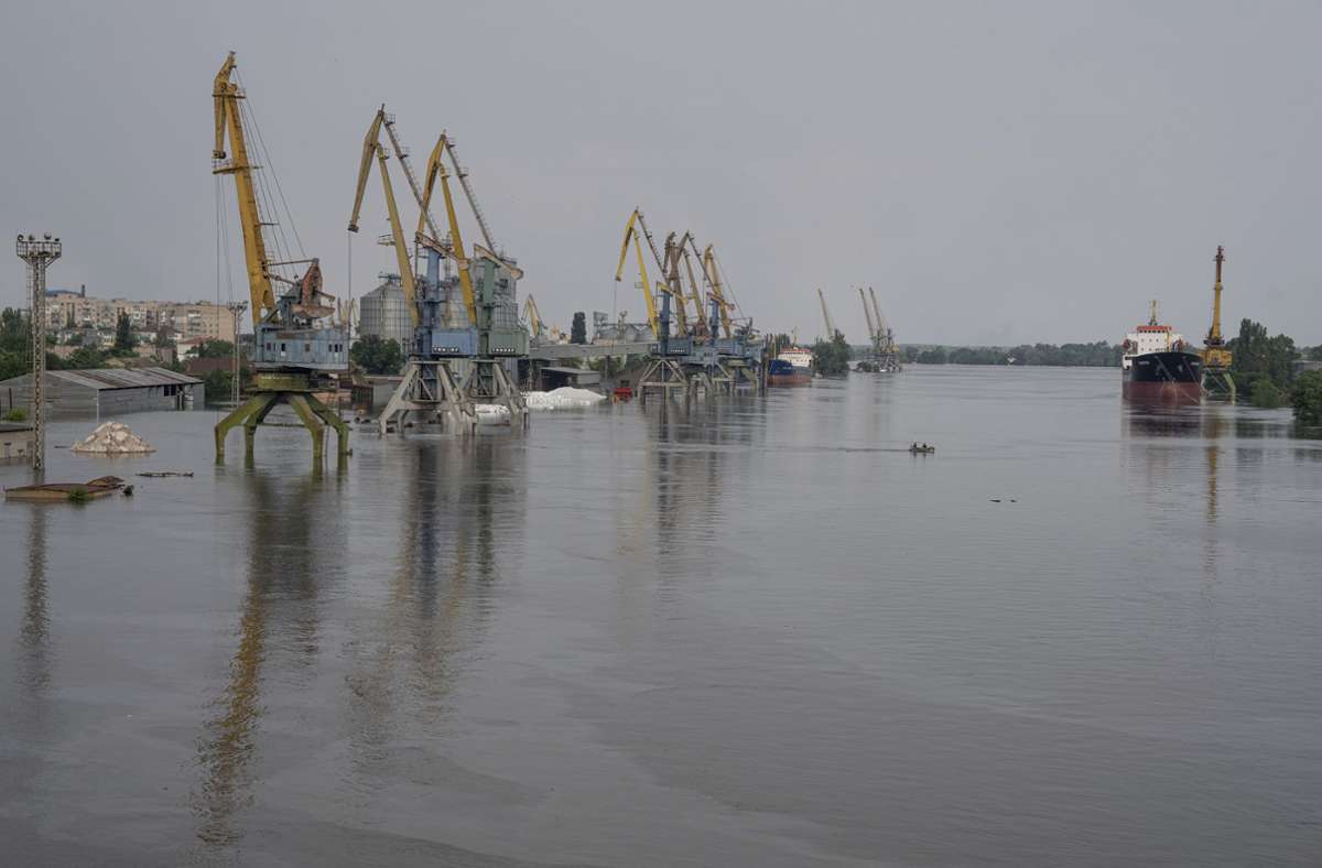 Ein Boot fährt durch einen überfluteten Handelshafen in Cherson. Der Staudamm in der Stadt Nowa Kachowka war in der Nacht zum Dienstag in dem von Russland besetzten Teil des südukrainischen Gebiets Cherson zerstört worden.