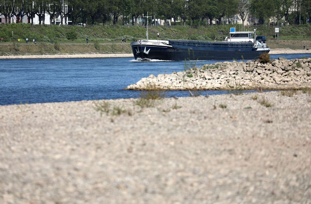 Ein Schiff fährt hinter einer freiliegenden Sandbank über den Rhein bei Köln. Der niedrige Wasserstand des Rheins belastet die Binnenschiff-Fahrt. Foto: Oliver Berg/dpa