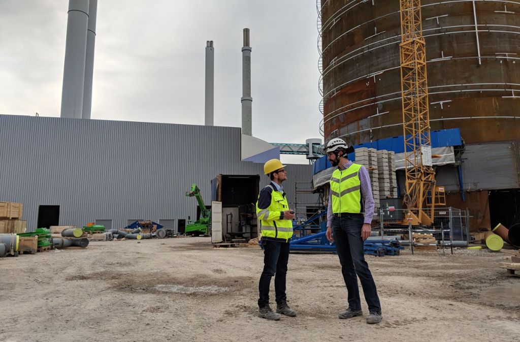 Der Projektleiter Jens Rathert (links) und der Oberbauleiter Christoph Greiner diskutieren vor dem 40 Meter hohen Wärmespeicher technische Details.