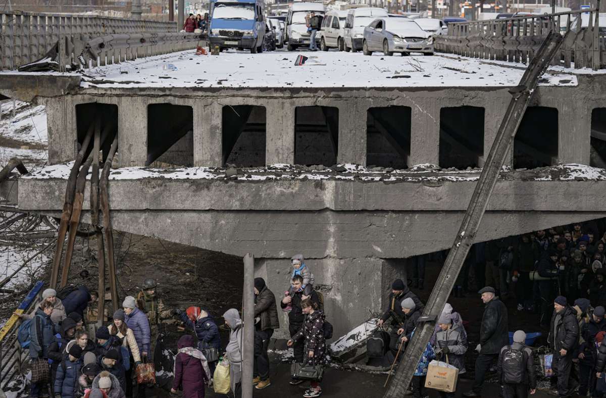 Leerstehende Fahrzeuge von Geflüchteten auf einer zerstörten Brücke in Irpin (Ukraine), während die Menschen die Stadt verlassen.