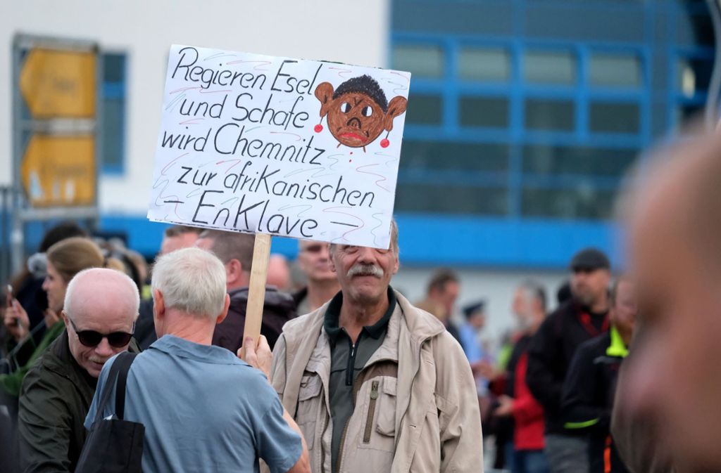 Demonstranten mit einem Schild „Regieren Esel und Schafe wird Chemnitz zur afrikanischen Enklave“ stehen von dem Stadium vom Chemnitzer FC.