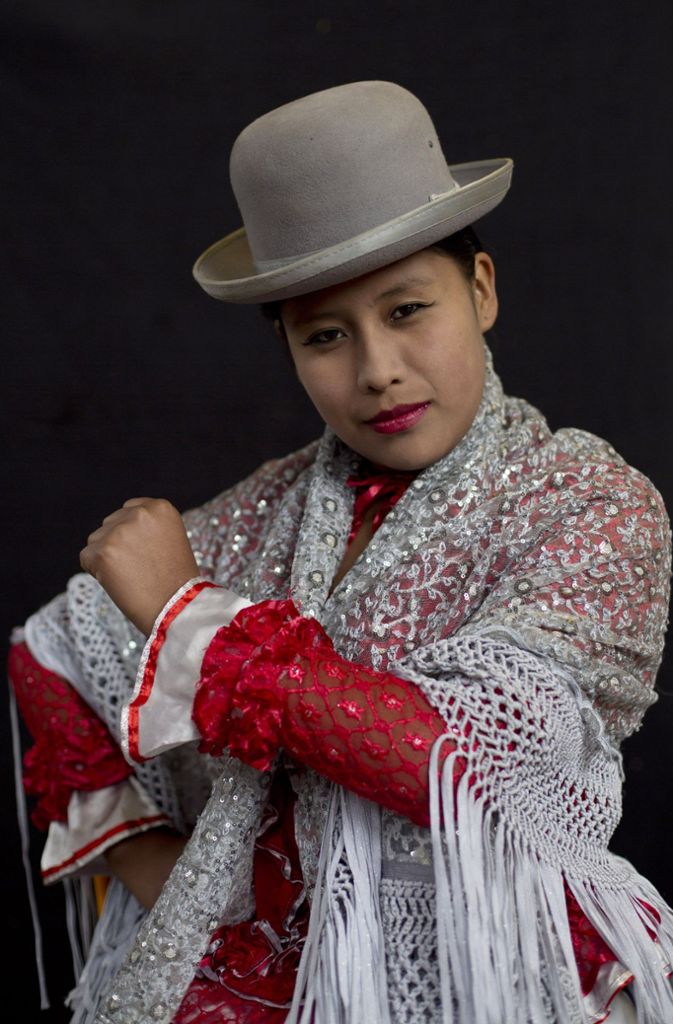 Cholitas, so heißen die indigenen Frauen Boliviens. Eine Cholita trägt viele Schichten Unterröcke, ein Schultertuch und dicke geflochtene Zöpfe. Auf ihrem Haupte hält, wie durch Zauberei, ein hoher Hut. Es heißt, eine englische Hutfirma habe in den 1920er Jahren Hunderte der Herren-Hüte aus Versehen zu klein produziert. Und diese dann in Bolivien als „europäischen Trend“ verkauft.
