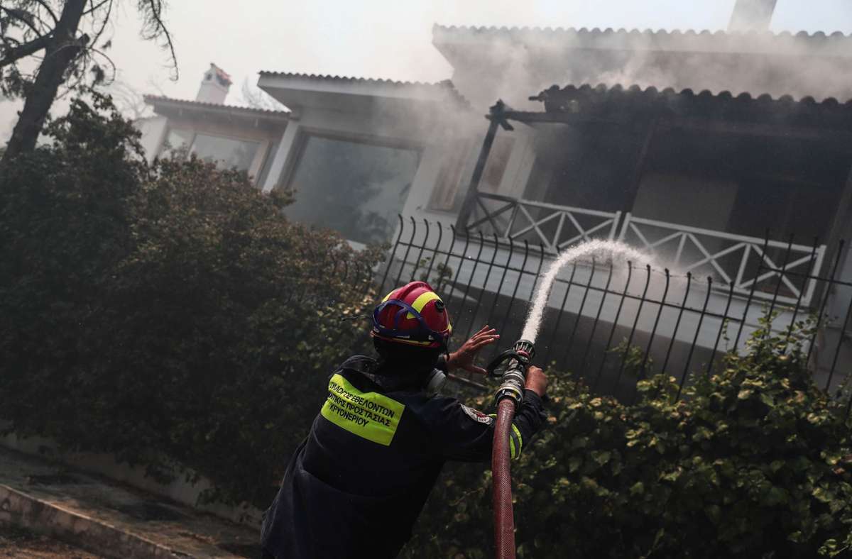 Ein Feuerwehrmann versucht, ein Feuer in einem Haus in dem Dorf Stamata in der östlichen Region Attika, Griechenland, zu löschen.