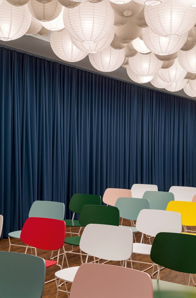Meetingraum im Büro Futurice mit einem Himmel aus japanischen Papierlampions und leuchtenden Farben bei der Möblierung der stapelbaren Stühle. Der Vorhang trennt den Küchen- vom Versammlungsbereich.