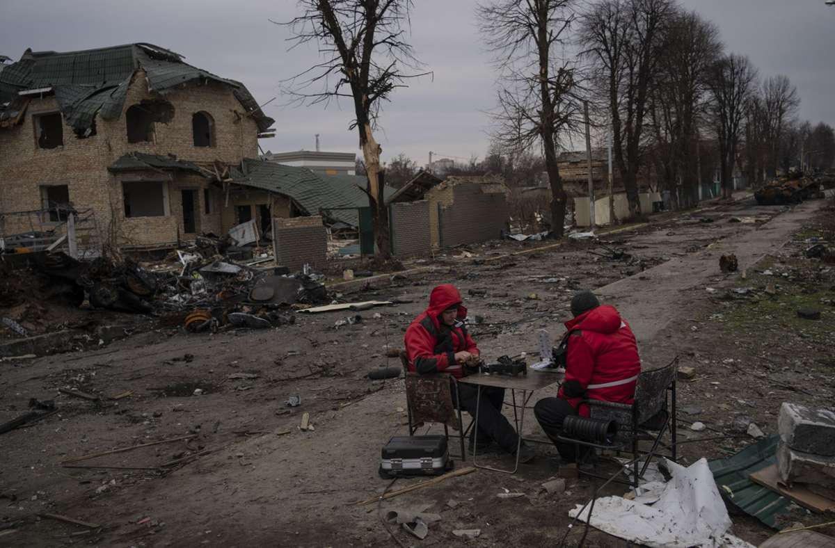 Zwei Techniker sitzen auf einer Straße in Butscha an einem Tisch und versuchen das Internet zu reparieren.