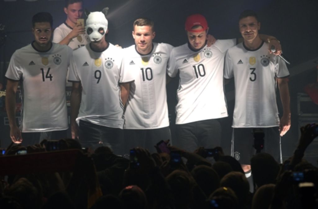 Die Fußballnationalspieler Emre Can (links), Lukas Podolski (Mitte) und Jonas Hector (rechts) posieren mit Rapper Cro in den neuen Leibchen.