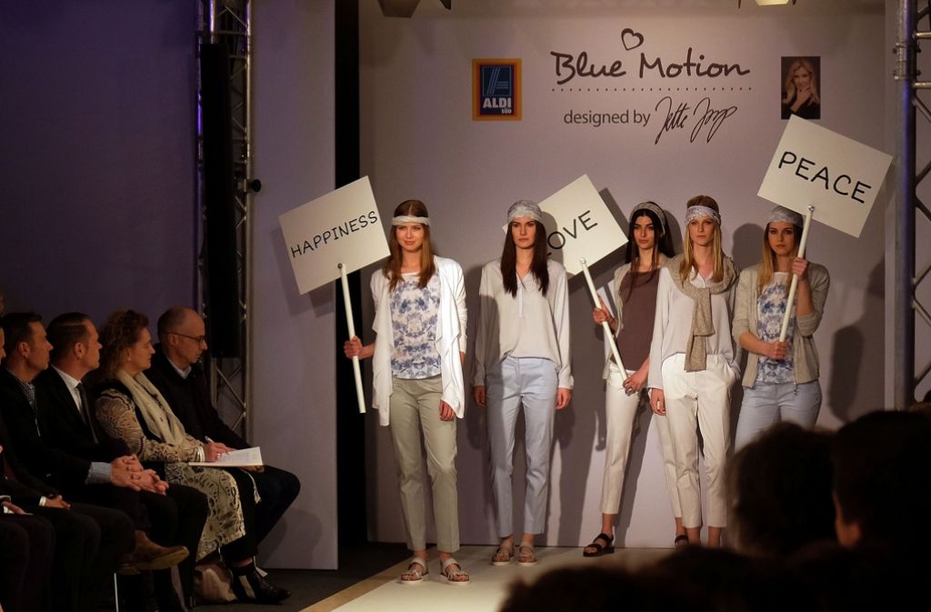 Die Models halten bei der Modenschau Schilder mit dem Schriftzug „Love“ oder „Peace“ in die Höhe – passend zur Kollektion, die mit Tüchern und floralem Muster an den Hippie-Look erinnert.