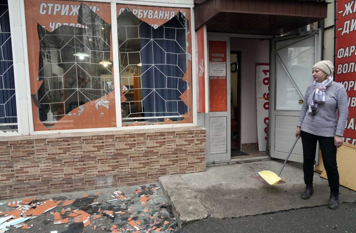 Eine Ladenbesitzerin fegt vor ihrem Geschäft in Kiew Scherben und Trümmer zusammen.