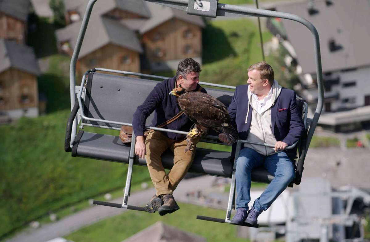 Hape Kerkeling (r.) und Falkner Norman Vögeli während der Lift-Fahrt mit einem Adler in Malbun