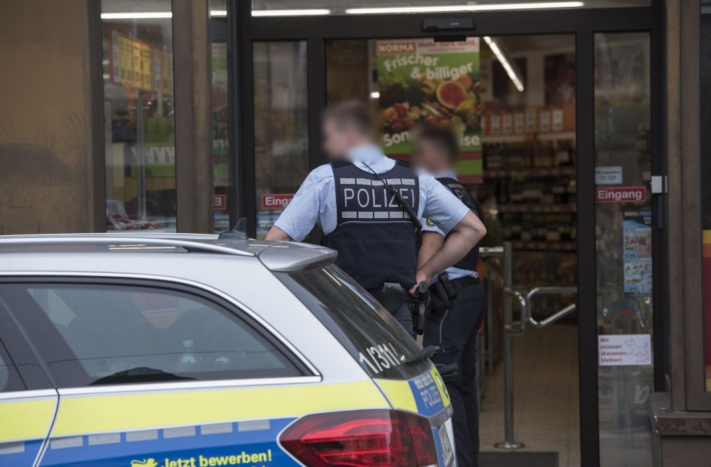 Polizisten sichern nach dem Überfall den Eingang zu dem Supermarkt in Möhringen.