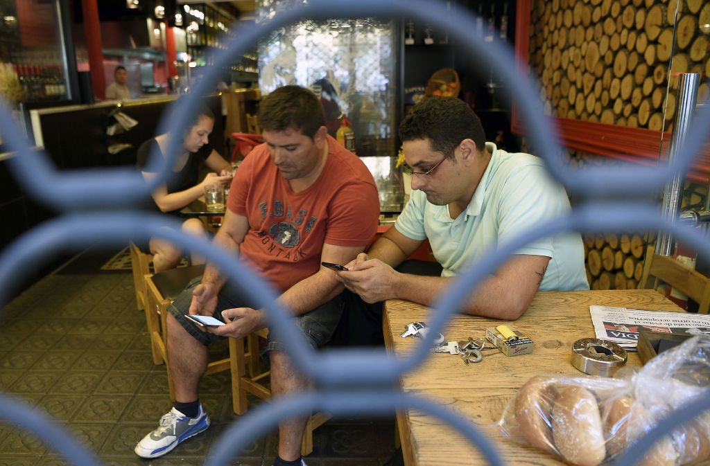 Menschen haben auch in Bars Schutz gefunden und informieren sich über ihre Smartphones über die neuesten Entwicklungen.
