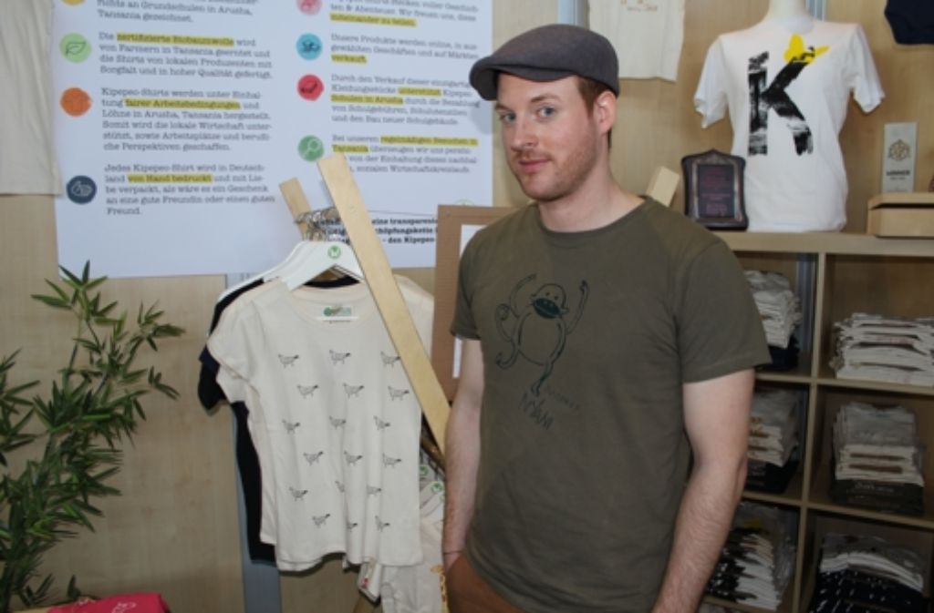 Martin Kluck am Stand von Kipepeo Clothing. Das neue T-Shirt ist mit Vogelmotiven bedruckt.