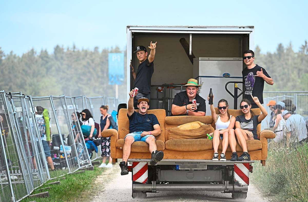 Festivalbesucher reisen gut gelaunt mit einem Kleinlaster an, auf dessen Rampe sie ein Sofa gestellt haben.