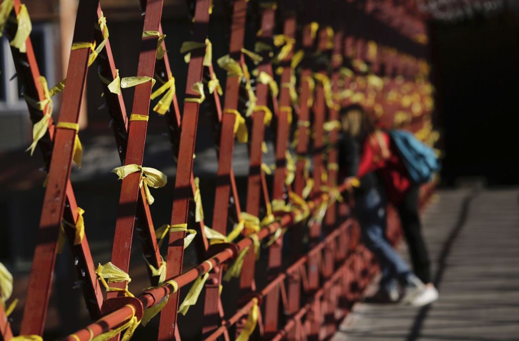 Ein Paar steht in Girona an einer Brücke, die mit gelben Schleifen geschmückt ist. Die gelbe Schleife dient als Symbol für die Unterstützung der inhaftierten Politiker der abgesetzten katalanischen Regionalregierung.