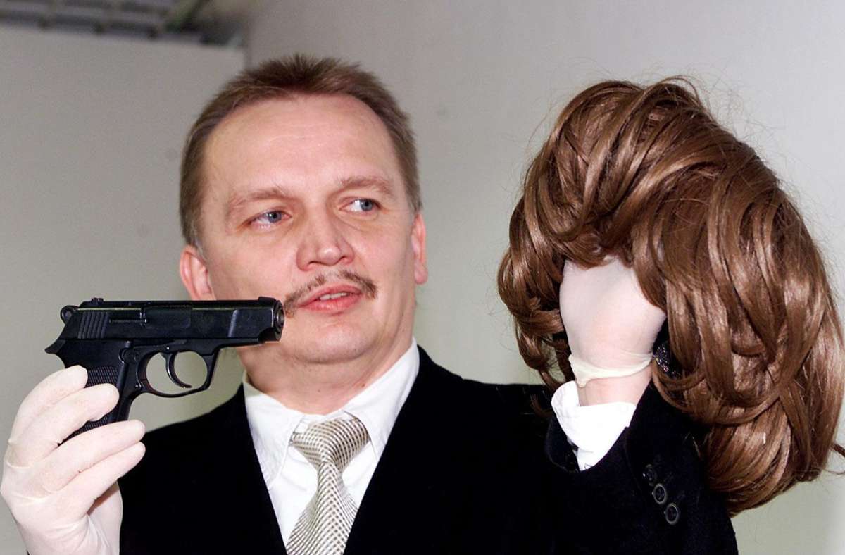 Der Ermittler zeigt eine Waffe und Frauenperücke der Serienbankräuber, die 2003 gefasst wurden.