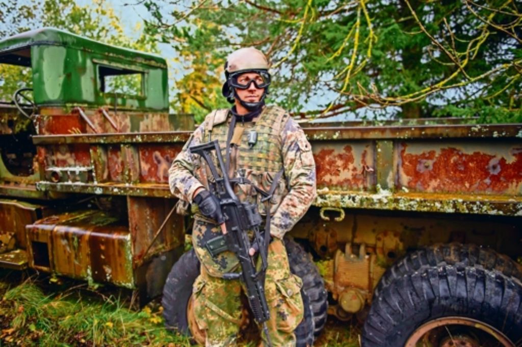 Ein schwer bewaffneter Infanterist vor einem ausgedienten Militärlastwagen.