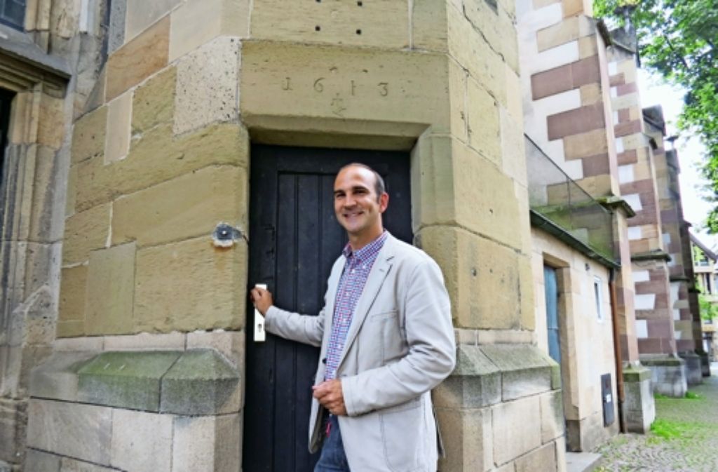 Pfarrer Florian Link am Turmeingang. Links neben der Tür ist die kleine Klingel. Auf dem Türsturz über dem Eingang ist das Baujahr zu erkennen.