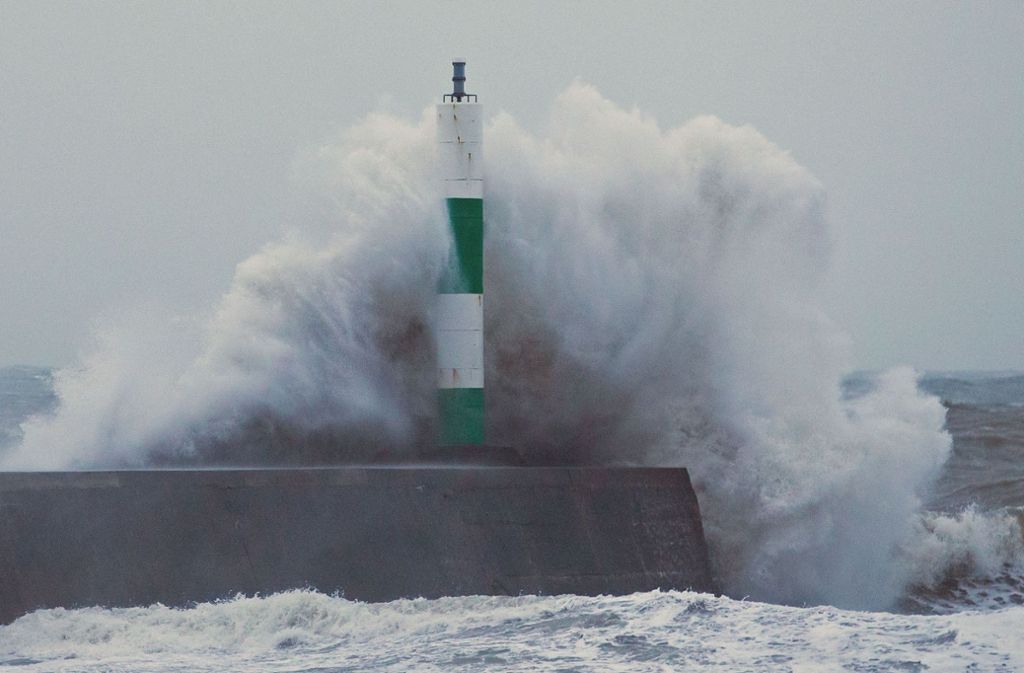 In Aberystwyth in Großbritannien brechen die Wellen an der Mauer einer Anlegestelle.