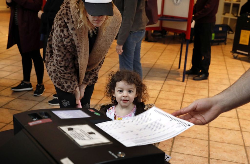 Falcon Wien (Mitte) schaut mit ihrer Mutter Sarah (links) zu, wie ihr Vater seinen Stimmzettel in dem Wahllokal der Presbyterianischen Kirche des Mount Kisco abgibt.