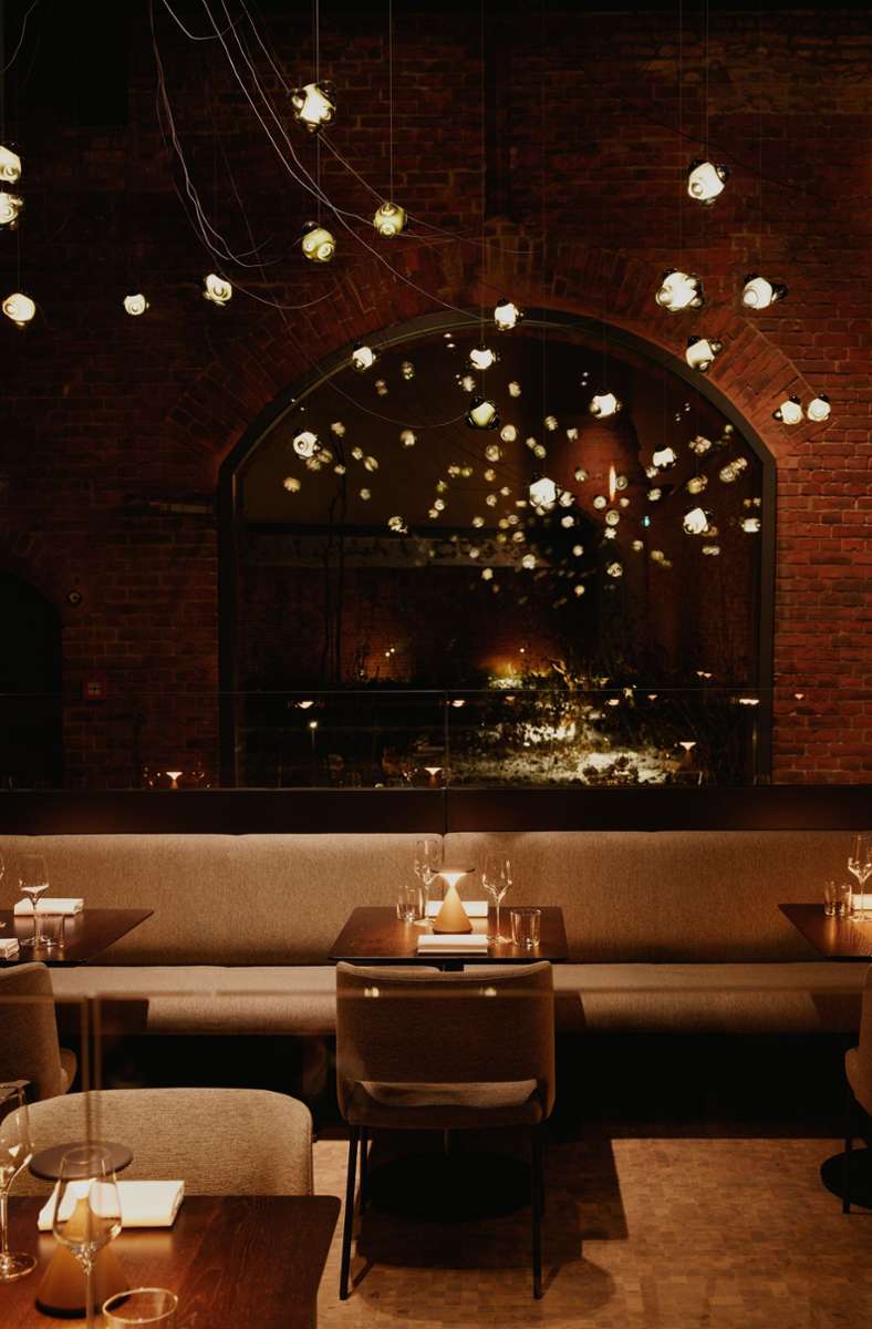 Die einstige Außenwand ist nun die Innenwand im Restaurant, die Lampen von Bocci vermitteln den Eindruck, dass es auch außerhalb des Raums leuchtet.