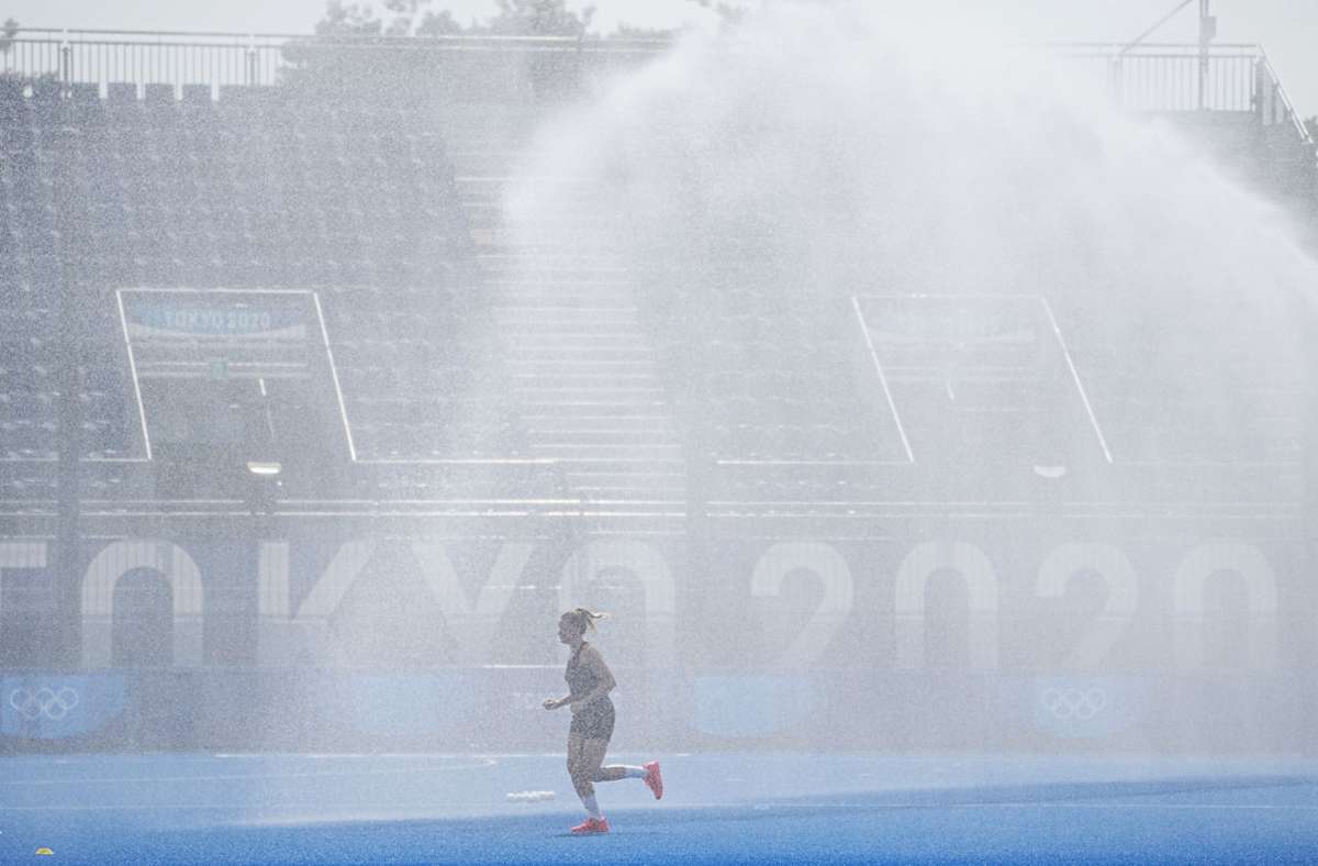 Eine deutsche Spielerin läuft vor Beginn der Partie zwischen der Bundesrepublik und Argentinien durch den Sprühregen der Platzbewässerung im Oi Hockey Stadium. Zu diesem Zeitpunkt ist es bereits 30 Grad heiß.