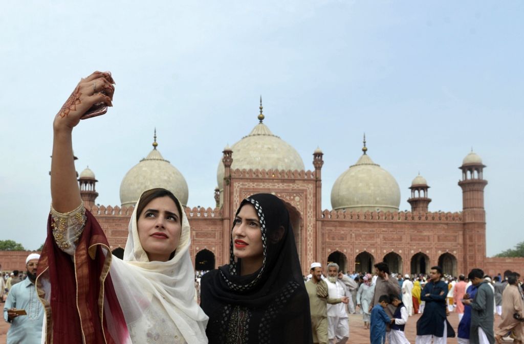 Fortschritt und Tradition: An der Badshahi Masjid in Lahore, Pakistan schießen zwei Frauen ein Selfie.