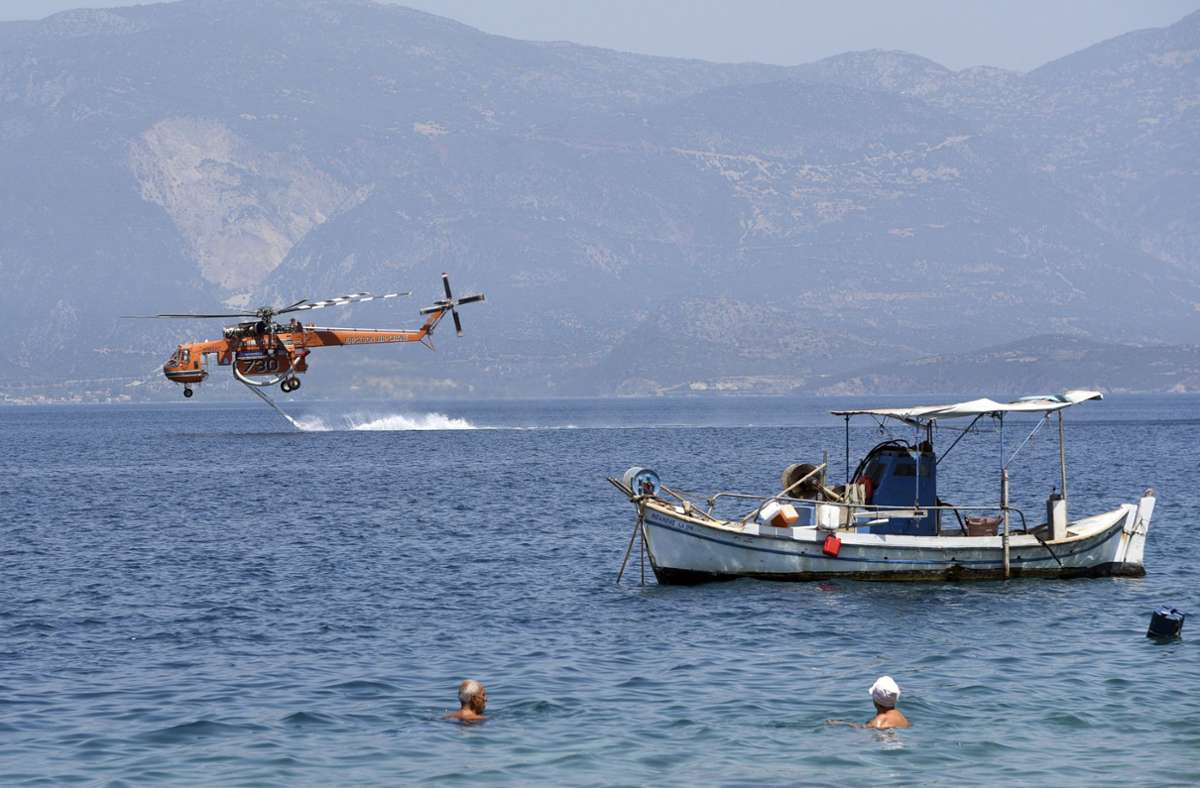 Ein Hubschrauber tankt in der Nähe des Dorfes Ziria Wasser aus dem Meer, um es über einem Waldbrand östlich der Stadt Patras abzulassen.