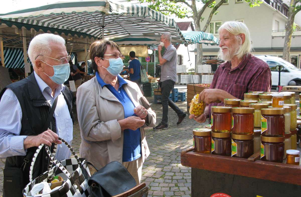 Imker Eckard Berlin berät Kunden an seinem Marktstand über seine Honigprodukte.