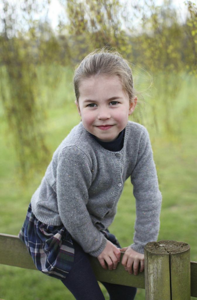 Mei, so süß! Prinzessin Charlotte im typischen Royal-Chic – graue Strickjacke und blauer Schottenkarorock – auf einem Zaun. Viele meinen, sie habe die Augen von Queen Elizabeth II, aber auch einiges von ihren Eltern.