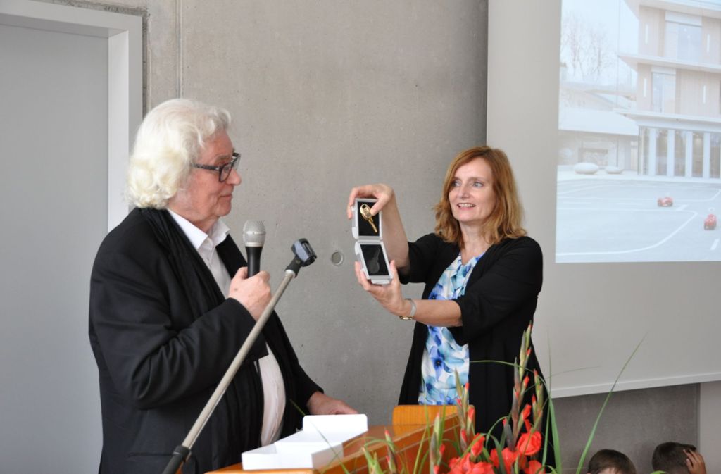 Architekt Günter Hermann übergibt den vergoldeten Schlüssel für das neue Kinderhaus an der Kirchhaldenschule an Isabel Fezer.